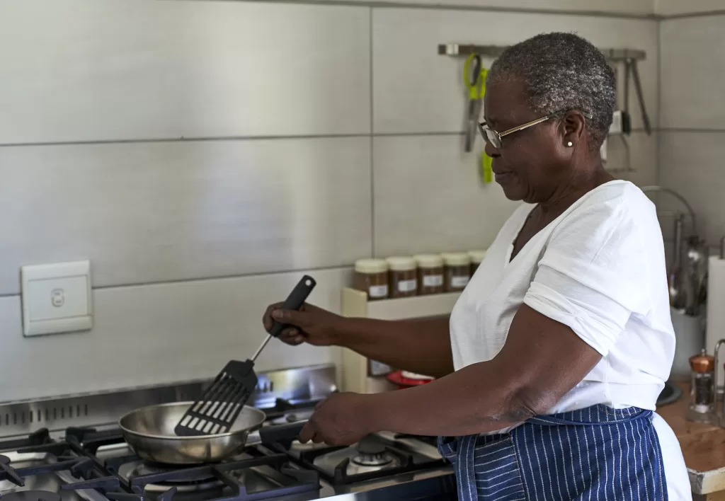 Senior woman cooking at gas stove in kitchen